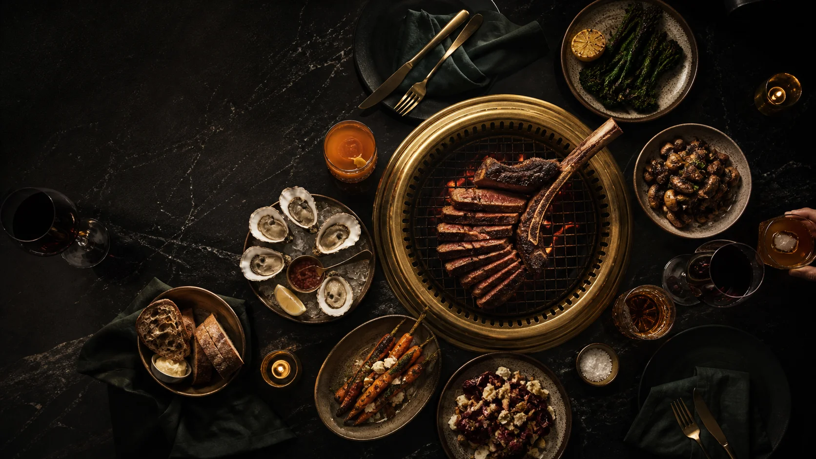 An overhead steakhouse feast arranged around a glowing brass grill